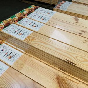Piles de lames de parquet en bois clair, emballées avec étiquettes LAQUET et dimensions 2000x140x140. Grain naturel visible.