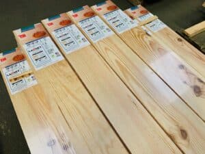 Piles de planches de parquet en bois clair Laouet Selection (2000x140x23mm) avec labels PARQUET À L'ANCIENNE, CE, A+, FSC/PEFC.