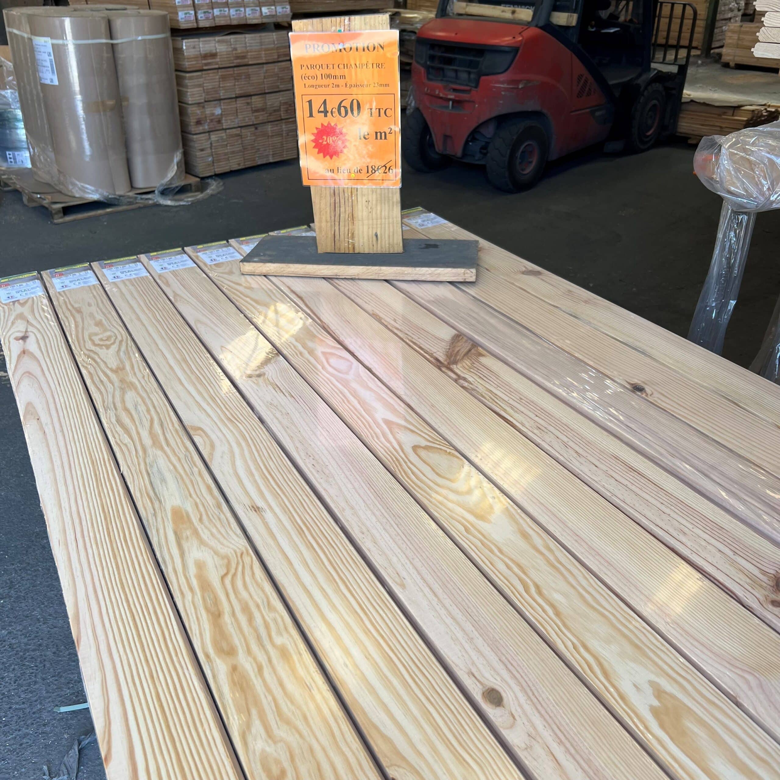 Lames de parquet champêtre empilées, en promotion. Panneau affiche "PARQUET CHAMPÊTRE" à 14€60 TTC/m², -20% au lieu de 18€26.