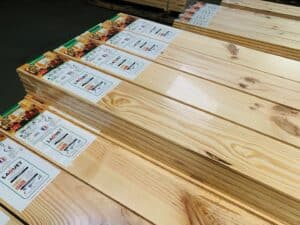 Piles de lames de parquet LAQUET TRADITION en bois clair. Étiquettes 'A+' et 'POSE FACILE' visibles avec dimensions.