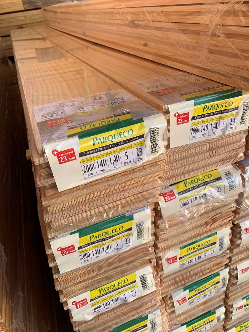 Piles de paquets de parquet Parqueco en pin des Landes, 23 mm d'épaisseur, lames de 2000x140 mm, 1,40 m² par paquet.