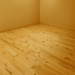 Coin de pièce vide avec parquet en bois clair et murs beiges, lumineux et prêt à être aménagé.