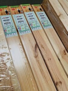 Paquets de lames de plancher en bois de sapin LAOUET TRADITION, emballées sous film. Labels affichent 2000x100x10 mm, pose facile.